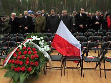 Teilnehmer der Gedenkfeier in Katyn stehen fassungslos vor den leeren Stühlen, auf denen Kaczynski und seine Mitreisenden hätten Platz nehmen sollen.