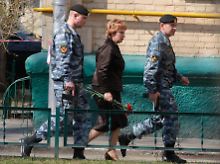 Olga Jegorowa, Vorsitzende des Moskauer Stadtgerichts, will in Begleitung ihrer Bodyguards eine Blume am Tatord niederlegen.