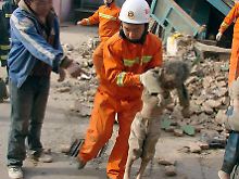Feuerwehrleute tragen ein Kind aus den Trümmern eines Gebäudes.