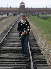 Eine Frau geht bei einer Gedenkfeier in Auschwitz die Gleise entlang.