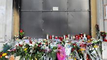 Blumen vor dem Bankgebäude, in dem die drei Menschen verbrannt sind.