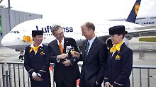 Umringt von zwei Flugbegleiterinnen stoßen Lufthansa-Chef Mayrhuber (l.) und Airbus-Chef Enders auf die Übergabe an.