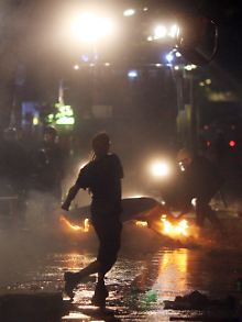 Ein Randalierer wirft im Hamburger Schanzenviertel einen Stuhl auf einen Wasserwerfer.