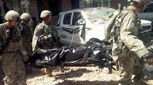Soldaten tragen einen Toten aus dem Gebäude.