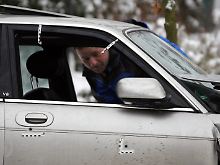 Ein Polizeibeamter schaut in das Auto, in dem der Kleinkriminelle erschossen wurde.