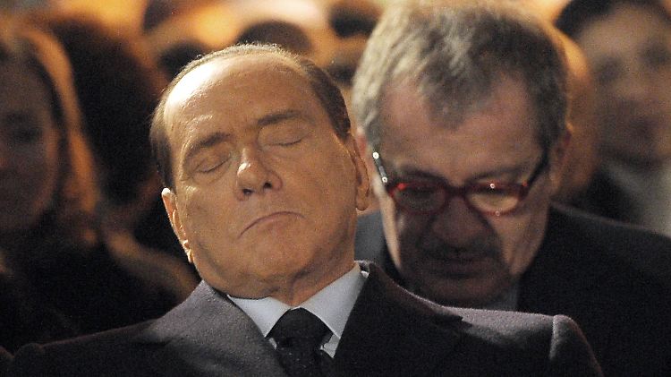 Silvio Berlusconi redet nicht nur Unsinn. Wie auf diesem Foto zu sehen ist, benimmt er sich während der Gedenkveranstaltung auch noch daneben. 