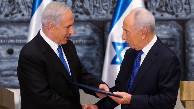 Netanjahu (l.) bekannt von Peres (r.) den Auftrag, aus einer Gruppe gegensätzlicher Parteien eine Regierung zu bilden.