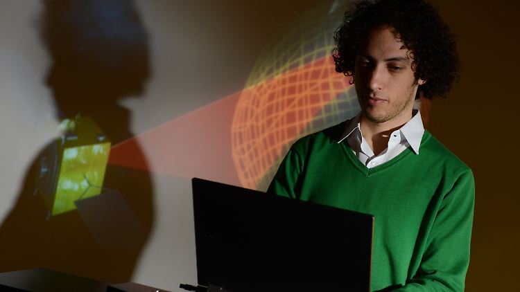 Noah Saks, Leiter des Projektes "Neoshield", beim Satellitenbauer Astrium vor einer Leinwandprojektion, die zeigt, wie ein Satellit einen Asteroiden scannt.