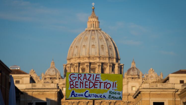 Ein Gläubiger hält in Rom auf dem Weg zur letzten Generalaudienz von Papst Benedikt XVI. vor der Kuppel des Petersdoms ein Schild mit der Aufschrift "Danke Benedikt" in die Höhe.