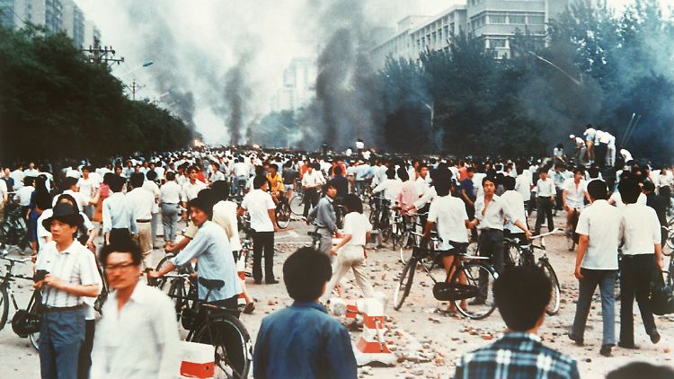 Rauchsäulen, Verwüstung und ratlose Menschen auf der Chang'an Avenue in Peking am 4. Juni 1989. Die Straße führt unmittelbar am Platz des Himmlischen Friedens vorbei.