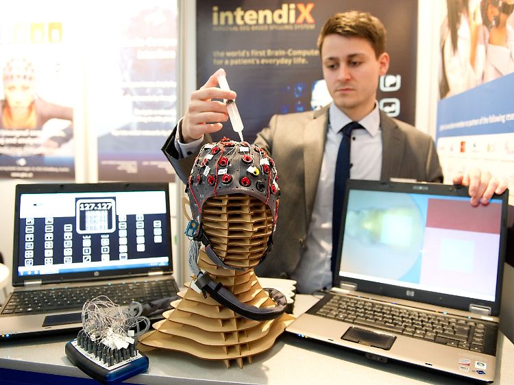 Armin Schnürer von g.tec injiziert mit einer Spritze Elektroden-Gel in eine EEG-Maske. Mit ihr können Nutzer allein durch Konzentration ein digitales Bild malen.