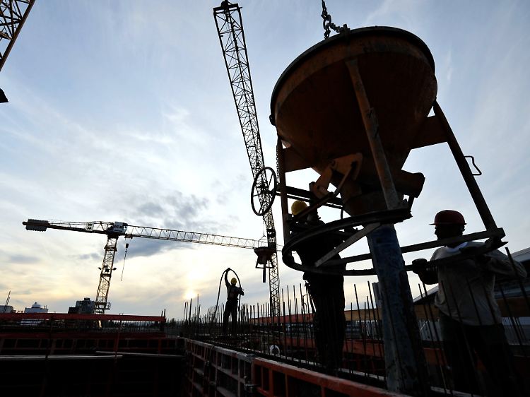 Arbeiter gießen auf der Baustelle eines Wohngebäudekomplexes in Frankfurt am Main Beton in die Verschalung.