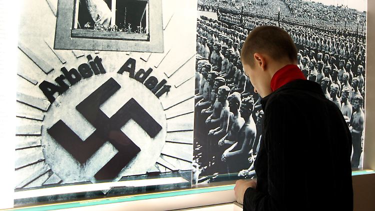 Eine Journalistin schaut sich Exponate einer Ausstellung über Zwangsarbeit im Deutschen Jüdischen Museum in Berlin an.