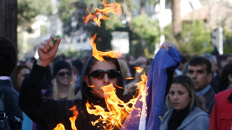 Bei einem Protest in der zyprischen Hauptstadt Nikosia verbrennt ein Demonstrant eine EU-Flagge.
