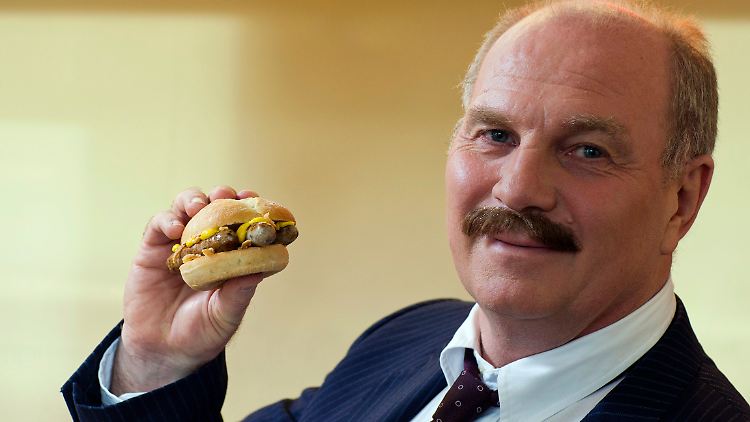 Uli Hoeneß bei Werbeaufnahmen mit einem Bratwurst-Burger.