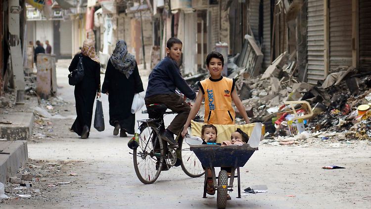 In Deir al-Zor kutschiert dieser Junge seine Brüder in einer Schubkarre durch die zerstörte Stadt.