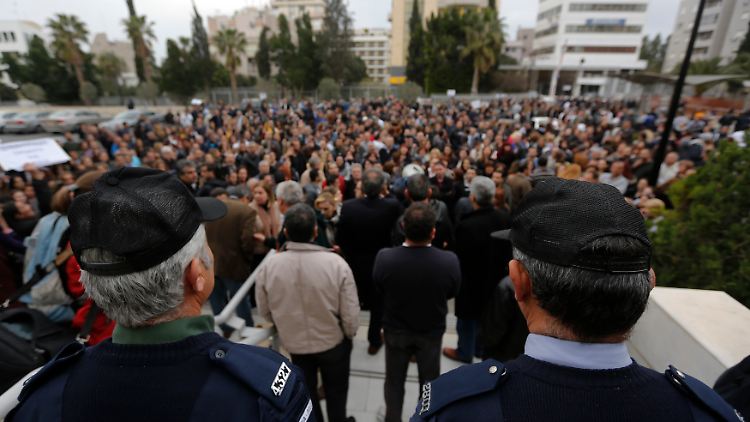 Polizisten bewachen Ende März den Eingang der Bank of Cyprus, während Angestellte vor dem Gebäude demonstrieren.