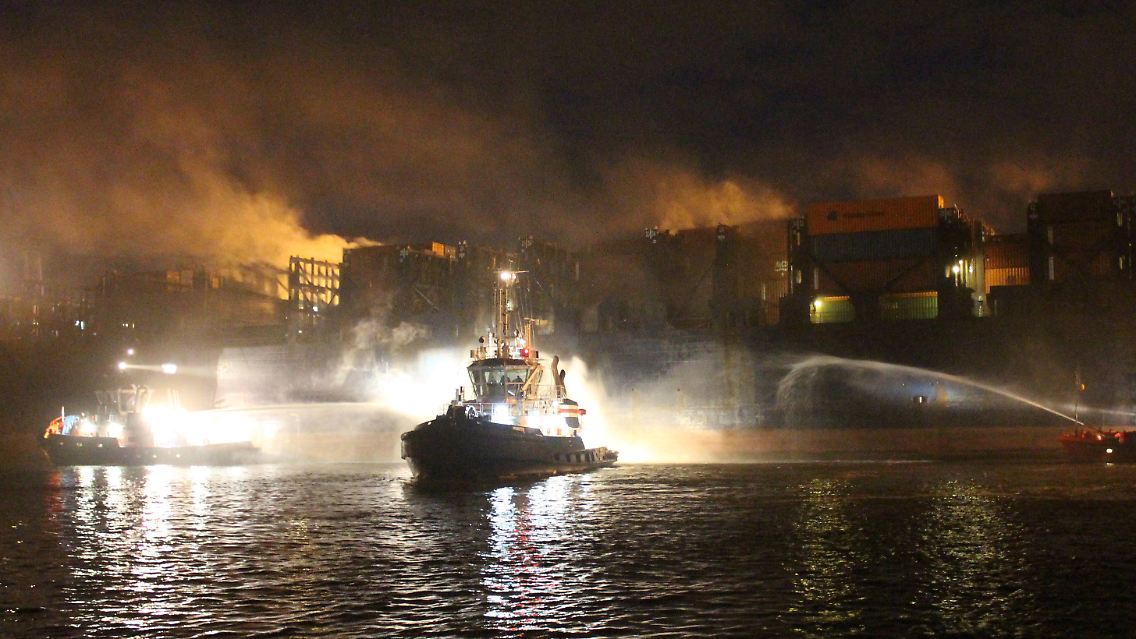 Die "Atlantic Cartier" hatte am 1. Mai  im Hamburger Hafen Feuer gefangen. Im Vordergrund ist ein Löschboot zu sehen.