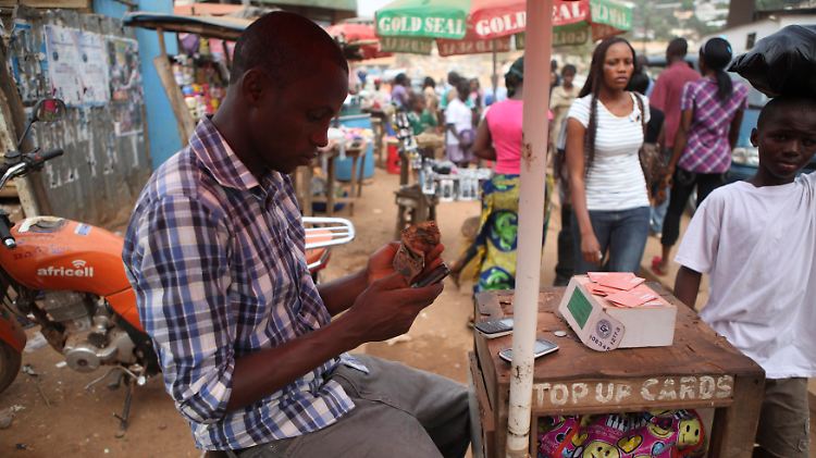 Junger Africell-Mitarbeiter an seinem Stand in Freetown, Sierra Leone. Die Mobiltelefonie ist in Afrika im letzten Jahrzehnt geradezu explodiert. Denn ohne flächendeckendes Festnetz ist sie die einzige Möglichkeit der Telekommunikation.
