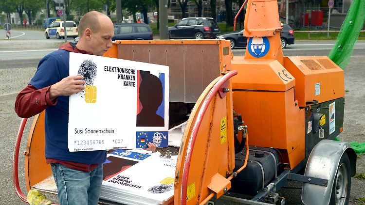 Bei einer Aktion der Freien Ärzteschaft werden mit einem Schredder überdimensionale Gesundheitskarten vernichtet.