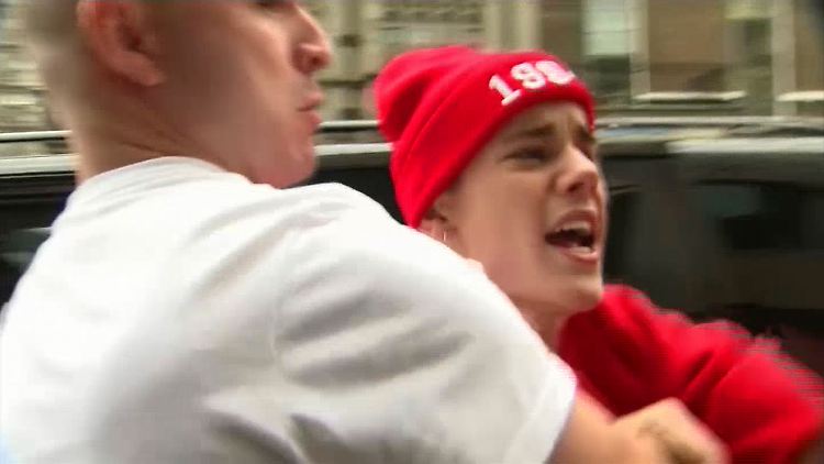 Ein Mitglied seines Security-Teams hält Justin Bieber zurück als er sich in London über einen Fotografen ärgert. (Archivbild 8. März 2013)