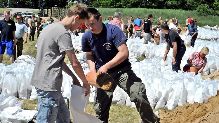 Freiwillige befüllen direkt an der Elbe in Bälow (Brandenburg) Sandsäcke.