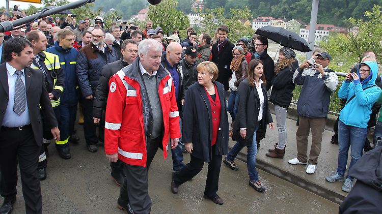 Besuch in Passau: Seehofer in Rettungsjacke und Gummistiefeln, Merkel in normaler Kleidung.