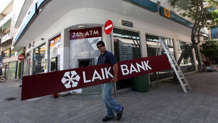 In Nikosia entfernt ein Handwerker ein Schild der geschlossenen Laiki-Bank.