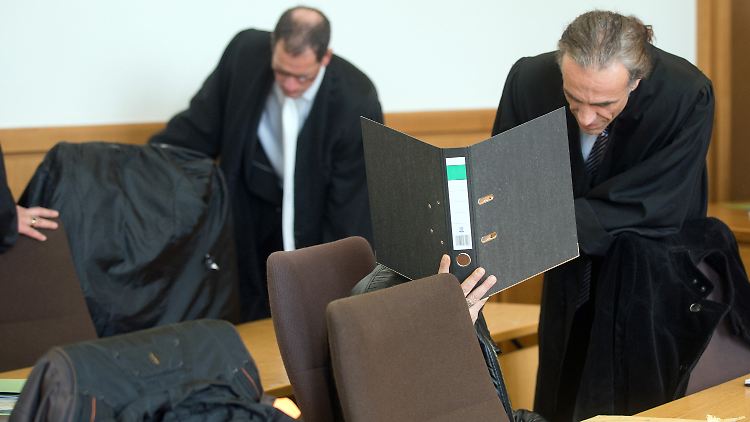 Die Angeklagte Mutter Aziza R. (l) und ein Onkel des Opfers, Hussain K. (2.v. r) verbergen sich auf der Anklagebank im Landgericht hinter einem Mantel und einem Aktenordner. Rechts Anwalt Frank Nobis, in der Mitte Anwalt André Neumann.