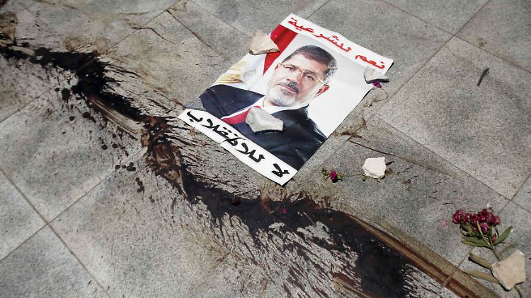 Das Blut von Demonstranten klebt neben einem Bild des gestürzten Präsidenten Mursi auf der Straße.