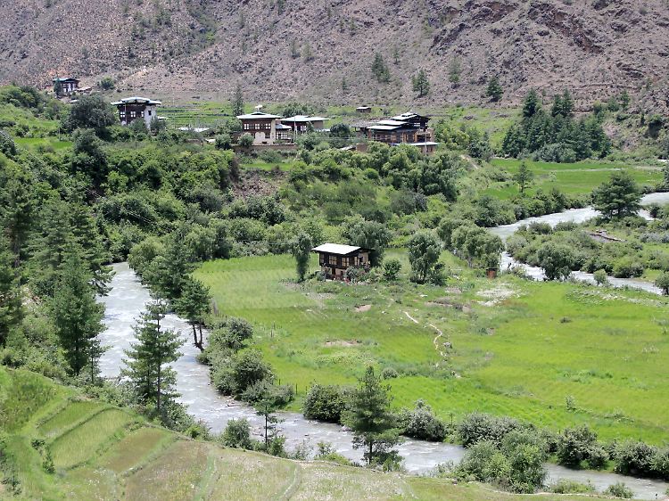 Häuser umgeben von Reisfeldern. Doch was in Bhutan angebaut werden kann, reicht nicht aus, um die Bevölkerung zu ernähren. Importe aus Indien sind nötig.