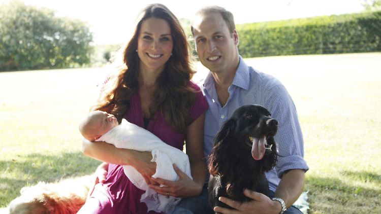In eine weiße Decke gehüllt, scheint der kleine Prinz zu schlafen. Den Eltern ist der Stolz über den Nachwuchs anzusehen.