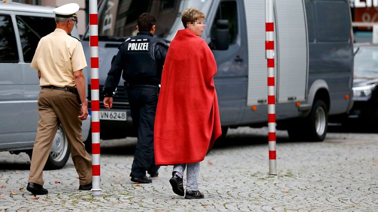 Polizisten begleiten nach dem Ende der Geiselnahme eine Frau, die offenbar zu den Opfern gehörte.