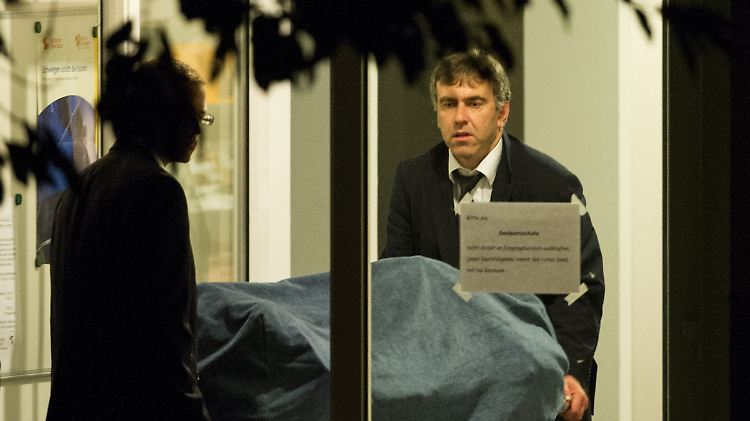 Bestatter tragen am Tatort die Leiche des Täters aus dem Gebäude.