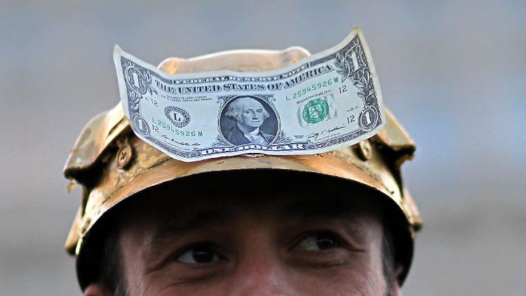 Ein Rumäne, der mit einem goldenen Helmauf dem Kopf mit einer Dollar-Note daran gegen das Goldminen-Projekt demonstriert.