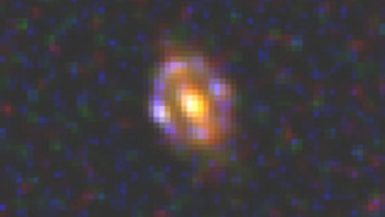 An der Grenze zur Sichtbarkeit: Die vordere Galaxie (Linsenmasse) erscheint orange gefärbt, die hintere Galaxie (Einsteinring) bläulich.