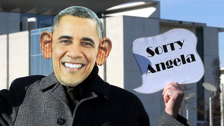 Ein Demonstrant, verkleidet als US-Präsident Barack Obama, hält ein Schild, auf dem er sich für das Abhören von Merkels Handy entschuldigt.