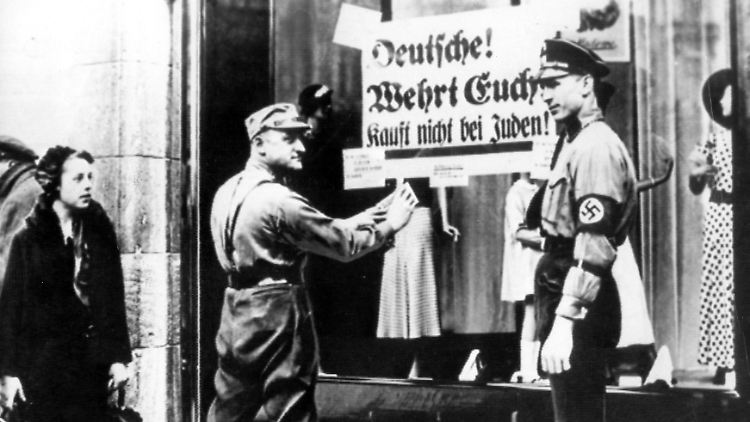 Nazis hängen Schilder an Geschäften auf, die befehlen, nicht bei jüdischen Händlern einzukaufen.