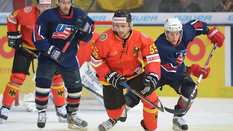 Der Deutsche Felix Schütz (M.) von Deutschland und der US-Amerikaner Steve Moses (r.) wetzen dem Puck hinterher. 