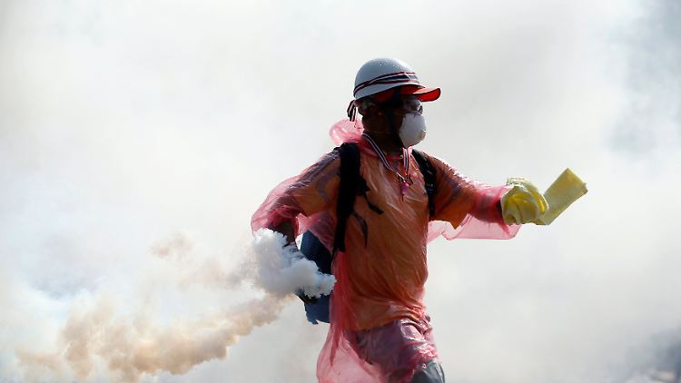 Vor dem Regierungssitz in Bangkok wirft ein Demonstrant Tränengas-Kartuschen auf die Polizei.