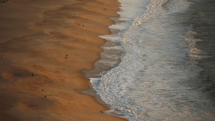 Die jungen Leute saßen am Meer, als sie von einer Welle überrascht und ins Wasser gezogen wurden.