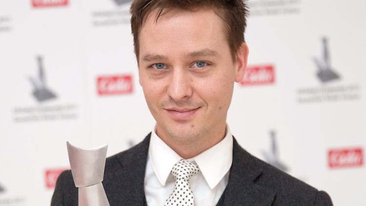 Mit einer weißen Krawatte mit dunklen Quadraten nahm Schilling seinen Preis entgegen.