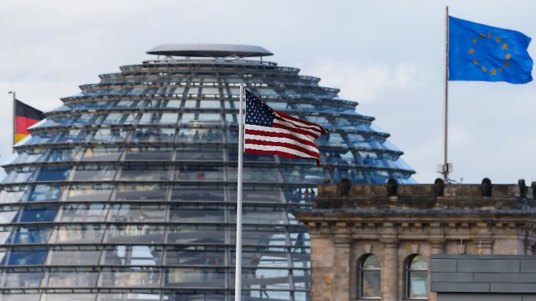 Die Flagge der USA weht über der US-Botschaft am Brandenburger Tor. Im Hintergrund der Reichstag mit drei deutschen und einer europäischen Flagge.