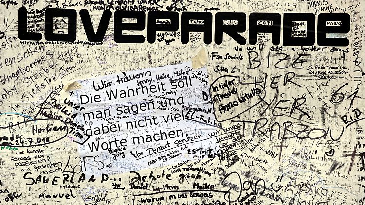 Ein von vielen Menschen beschriebenes Plakat am Gelände der Loveparade.