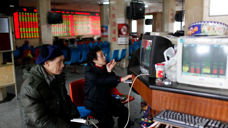 Bei einem Börsenmakler in Shanghai blicken Investoren auf Aktienkurse.