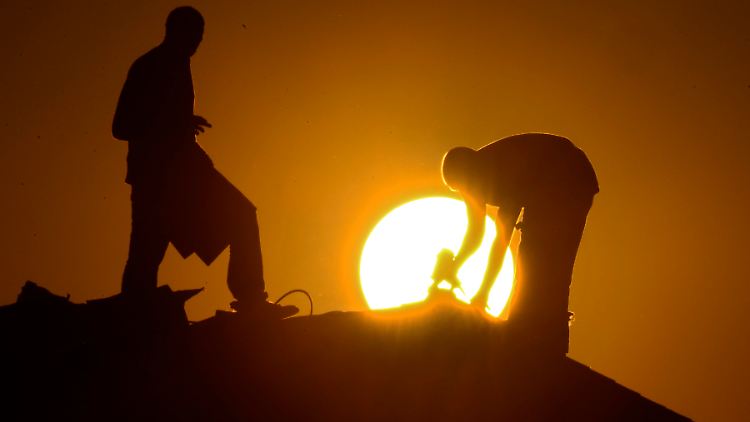Männer auf einem Hausdach: Begrünung oder Reflektoren auf Dächern sollen der Erderwärmung entgegenwirken können.