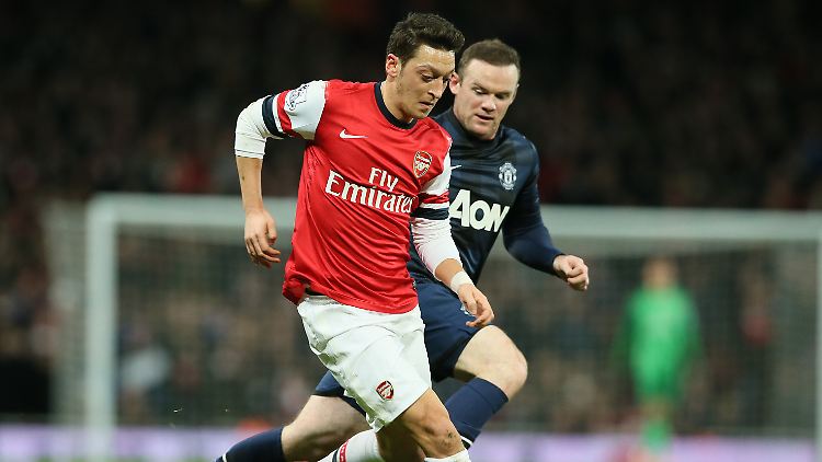 Mesut Özil schirmt den Ball gegen Wayne Rooney ab.