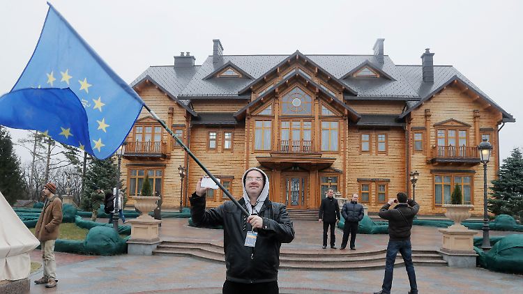 Vor der verlassenen Residenz des gestürzten Präsidenten schwenkt ein Mann die Fahne der EU. Häufiger ist in Kiew derzeit allerdings die blau-gelbe Flagge der Ukraine zu sehen - und die schwarz-rote der Vaterlandspartei von Julia Timoschenko.