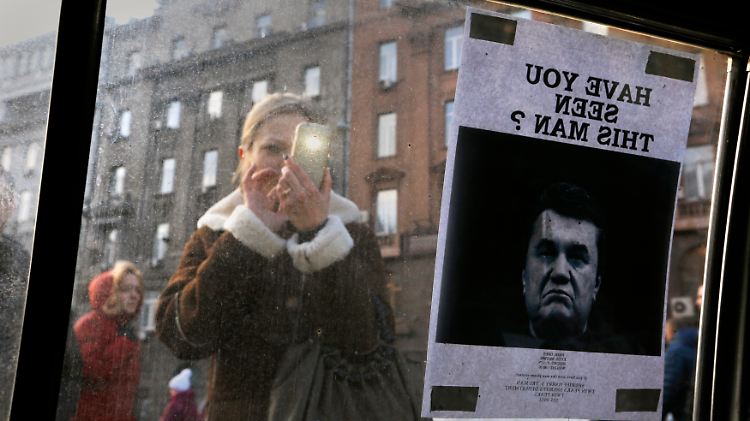 In Kiew fotografiert eine Frau ein Plakat auf dem Janukowitsch zu sehen ist - und die Frage: "Haben Sie diesen Mann gesehen?"