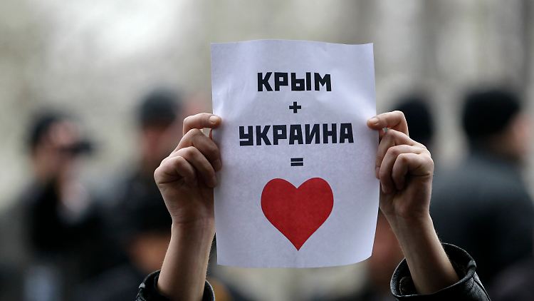 Bei einer Demonstration am 26. Februar vor dem Parlament in Simferopol hält ein Krimtatar einen Zettel hoch, auf dem steht: "Krim + Ukraine = Liebe".